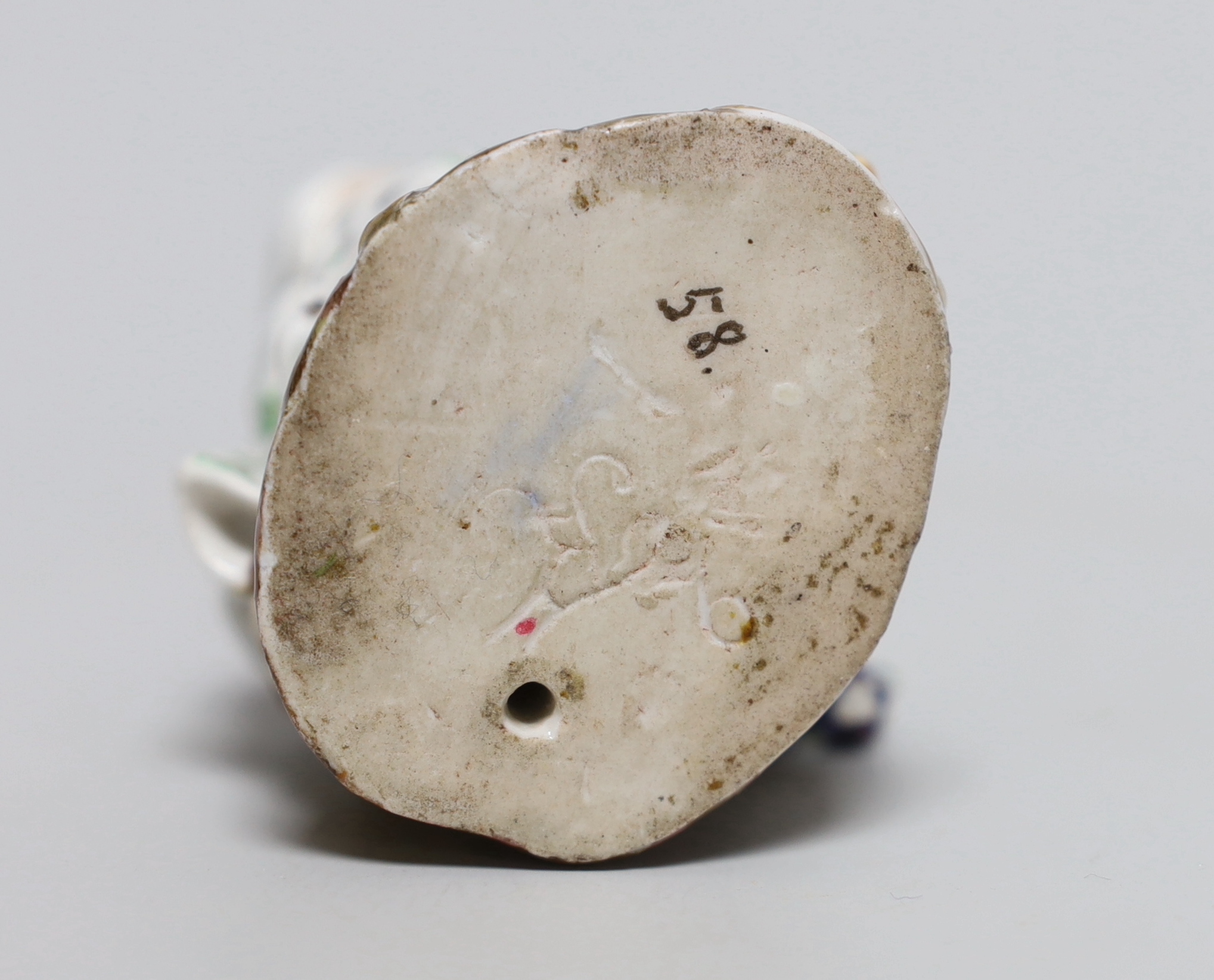 An early 19th century Meissen figure of a girl seated on a tree stump holding a bunch of grapes, painted 58, incised mark and feint crossed swords in blue, 11cm